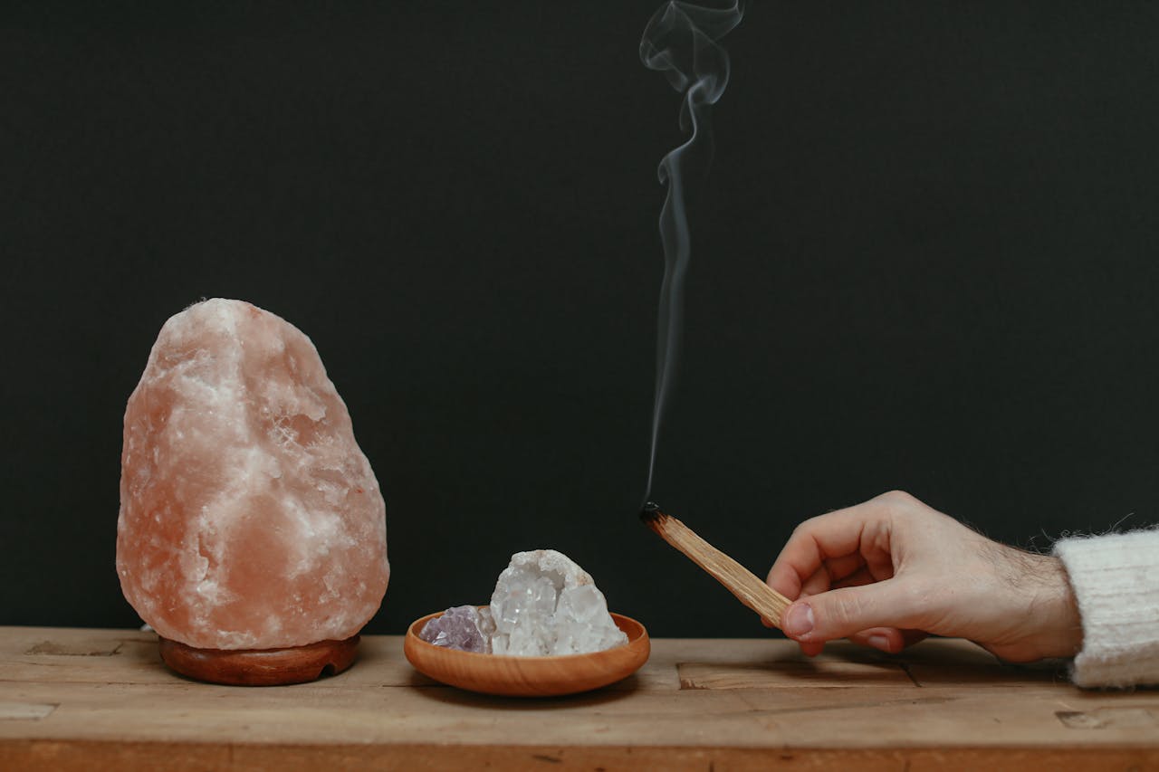 A serene setup with Himalayan salt lamp, healing crystals, and smoking palo santo for relaxation.