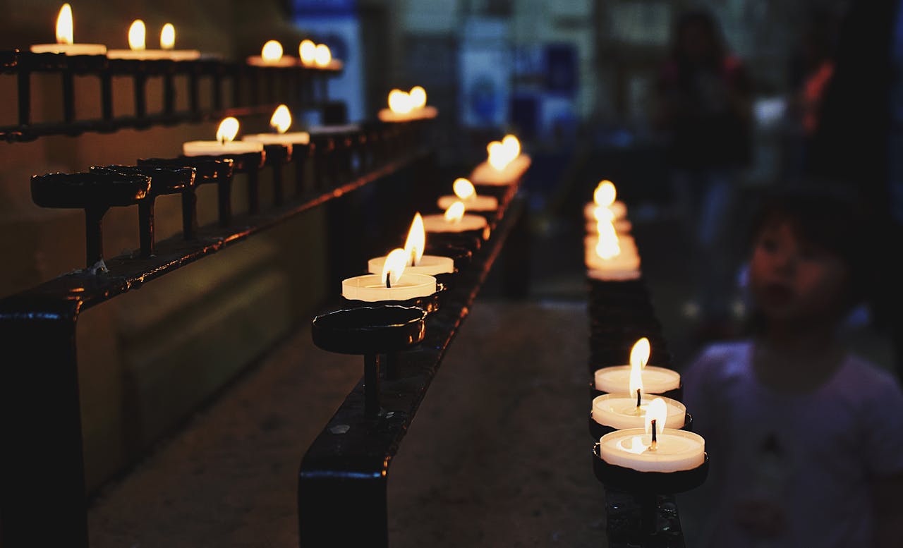 A serene church interior with lit candles on a metal stand, evoking a mood of contemplation.